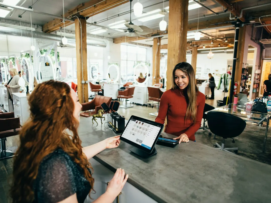 Recepción de un centro atendiendo a una clienta con una tableta